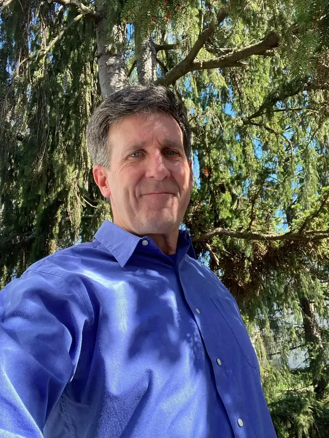 Long-time leader of the Coalition, Chris Combs, is shown in a grove of trees.