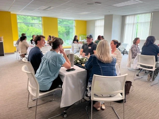 People attending an event, seated at tables and in conversation.
